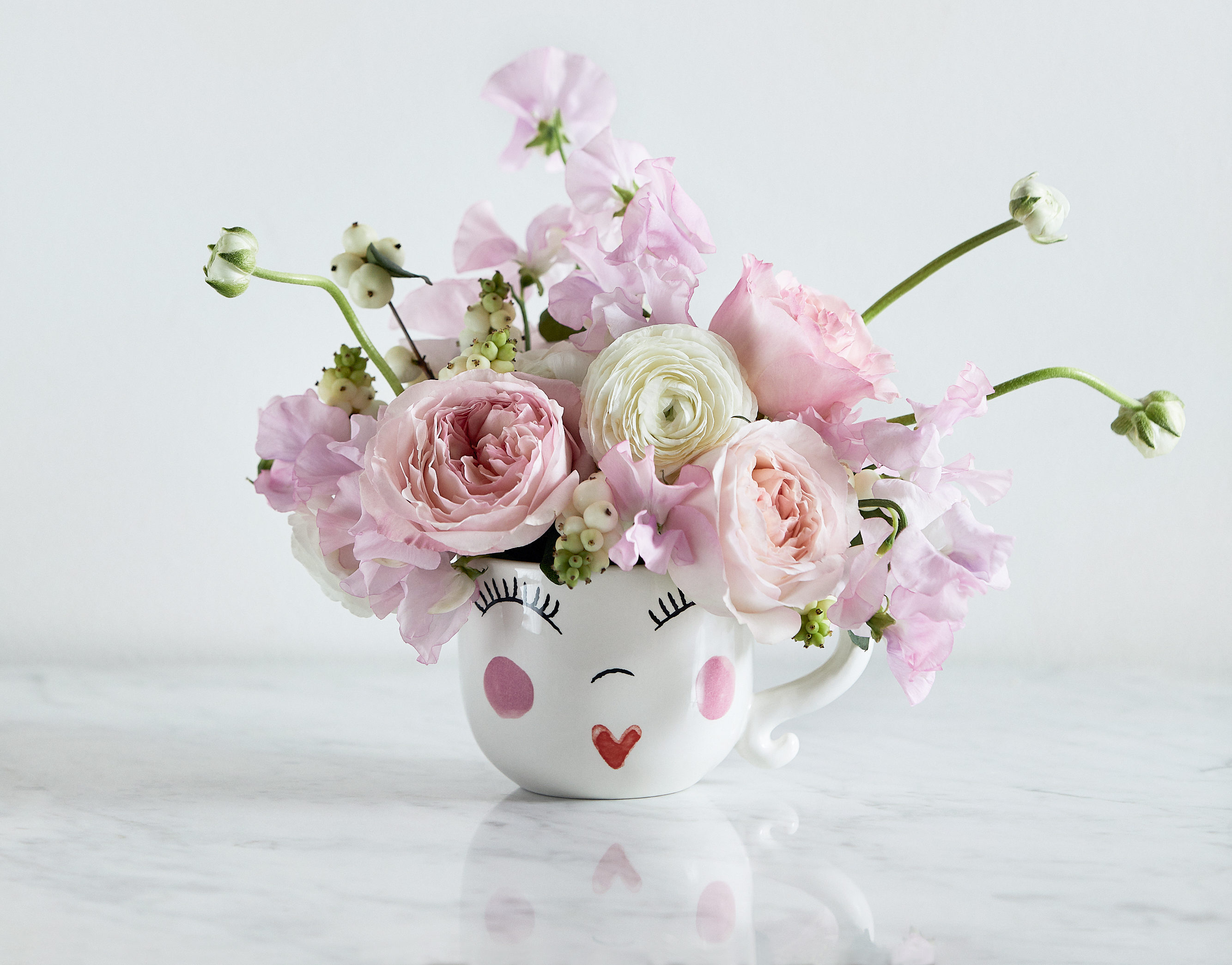 Smiley mug filled with sweet peas and garden roses